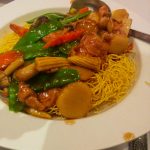 Chinese food with some micro vegetables over noodles.